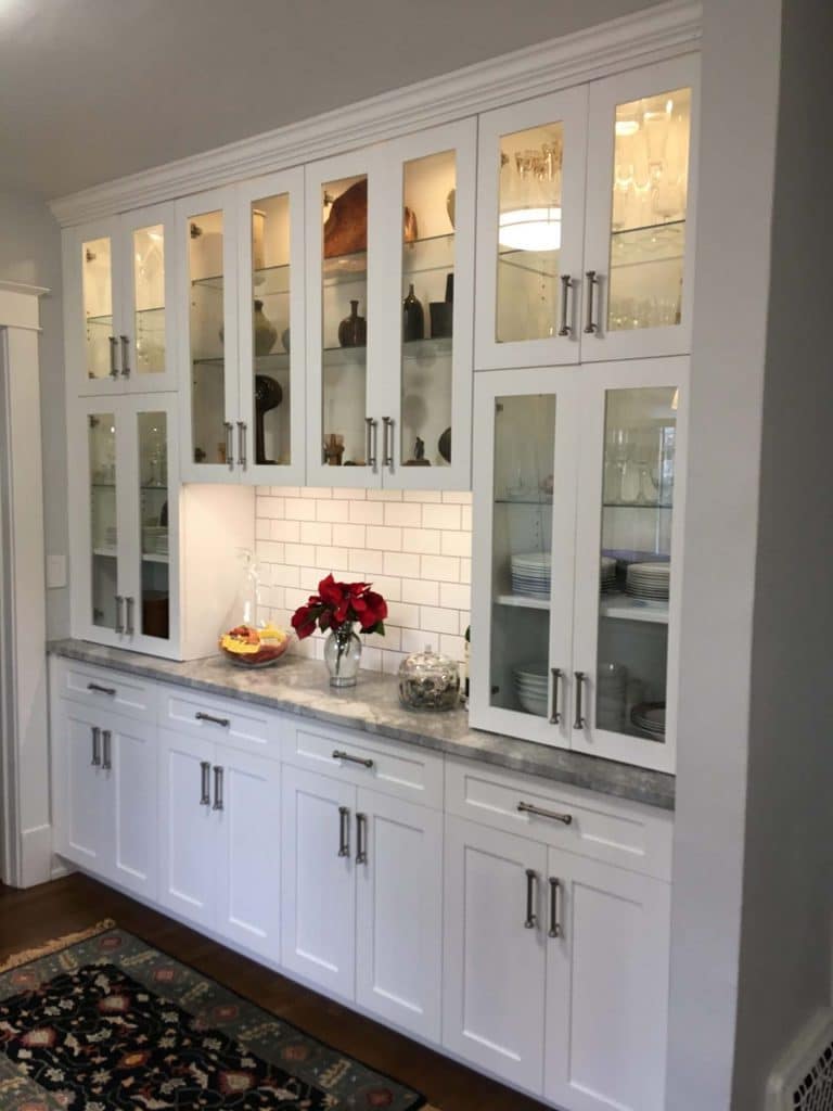 White kitchen with white cabinets and backsplash along with a hardwood floor